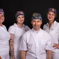 Zespół gabinetu stomatologicznego w Łodzi w kolorowych czepkach i białych uniformach.