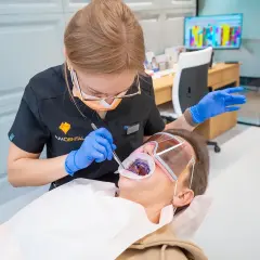 Profesjonalna higienistka stomatologiczna wykonuje zabieg wybielania zębów.
