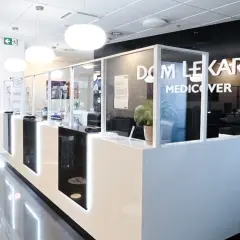 Nowoczesna recepcja w klinice Medicover z białym ladą, szklanymi przegrodami i logo.