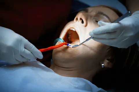 Dentysta bada jamę ustną pacjentki. Czy antybiotyk pomoże na ropień zęba?