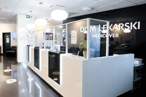 Nowoczesna recepcja w klinice Medicover z białym ladą, szklanymi przegrodami i logo.