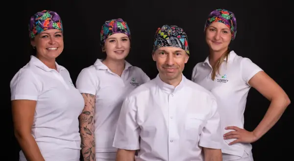 Zespół gabinetu stomatologicznego w Łodzi w kolorowych czepkach i białych uniformach.