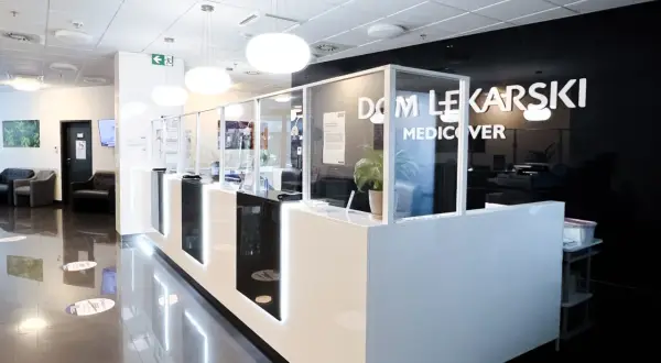 Nowoczesna recepcja w klinice Medicover z białym ladą, szklanymi przegrodami i logo.