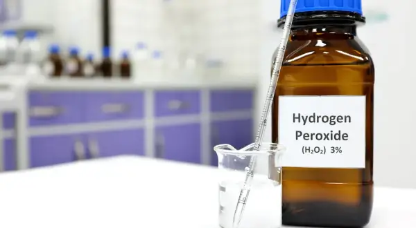 Nadtlenek wodoru zastosowanie w laboratorium: butelka z 3% H₂O₂ i zlewka z cieczą, w której zanurzony jest aerometr.