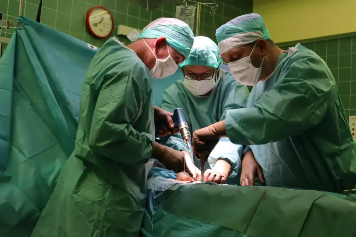 Trzech chirurgów w zielonych fartuchach i maseczkach wykonuje operację. Jeden z nich używa wiertarki chirurgicznej.