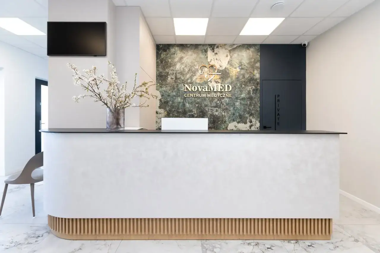 Nowoczesna recepcja centrum medycznego NovaMED z bukietem kwiatów i logo.