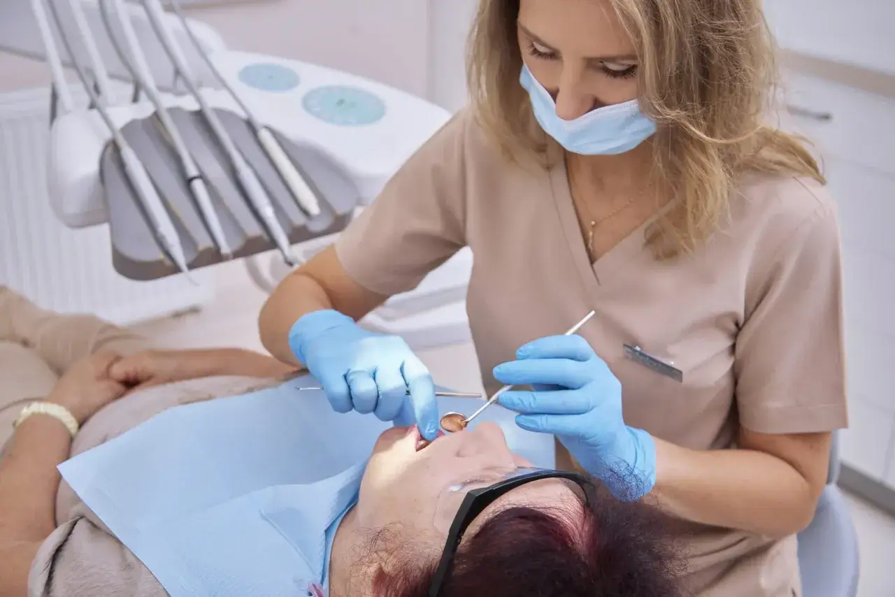 Dentystka bada pacjentkę, która zgłasza krwawiące dziąsła. Wczesne objawy mogą wskazywać na nowotwór.