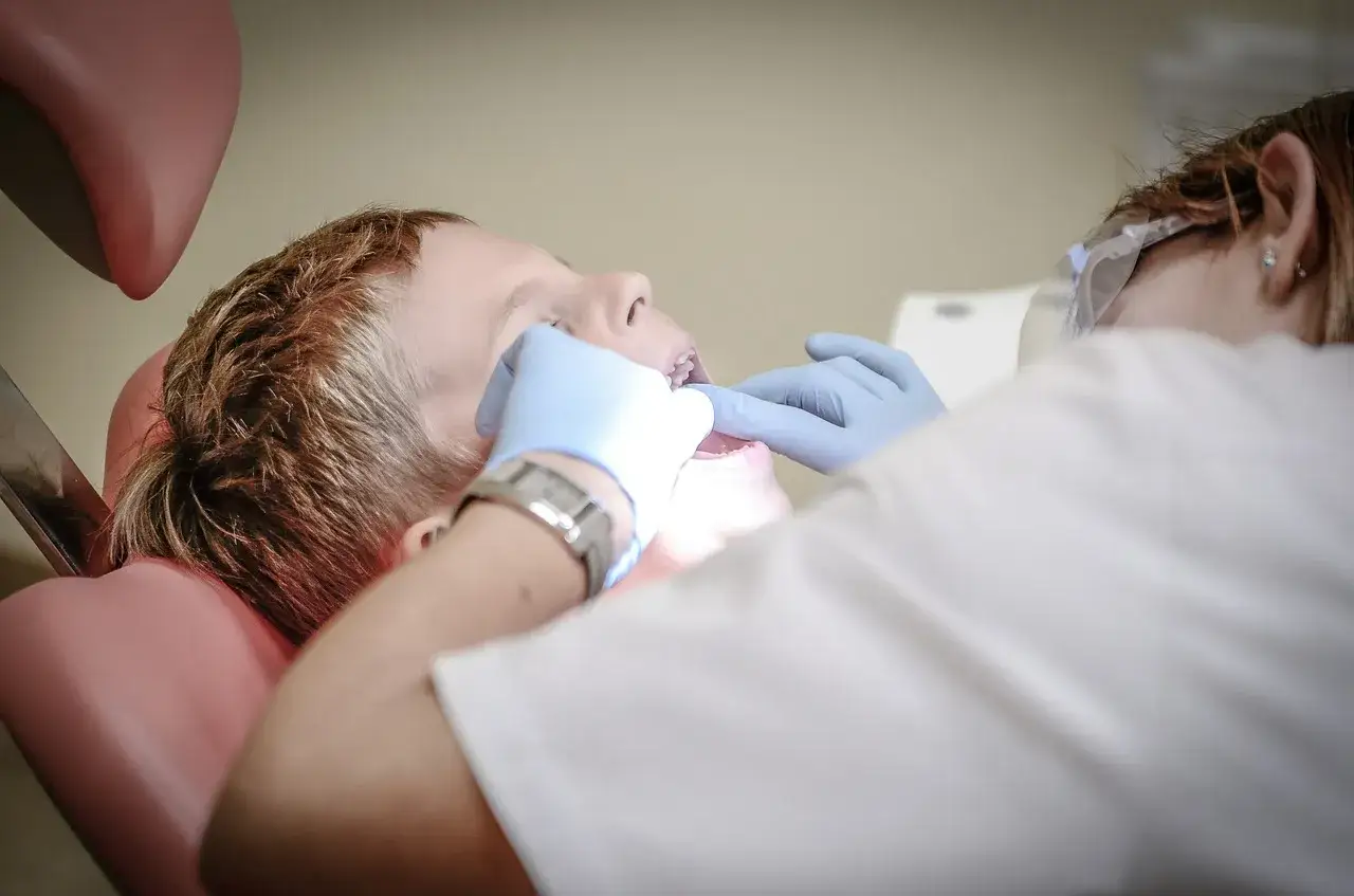 Chłopiec w gabinecie stomatologicznym, dentysta bada jego zęby. Wizyta u dentysty, nawet w ramach dentobusu, to ważny krok do zdrowego uśmiechu.