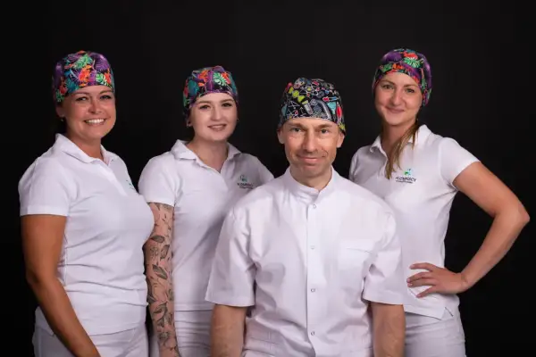 Zespół gabinetu stomatologicznego w Łodzi w kolorowych czepkach i białych uniformach.