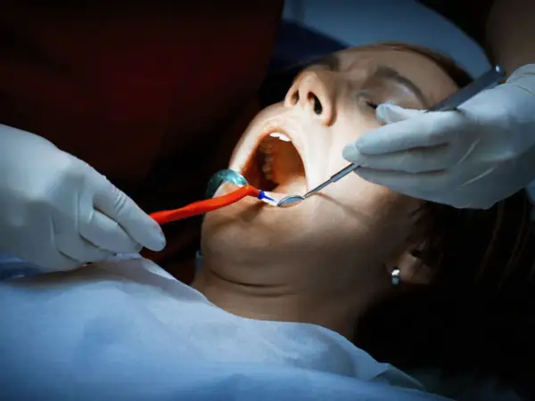 Dentysta bada jamę ustną pacjentki. Czy antybiotyk pomoże na ropień zęba?